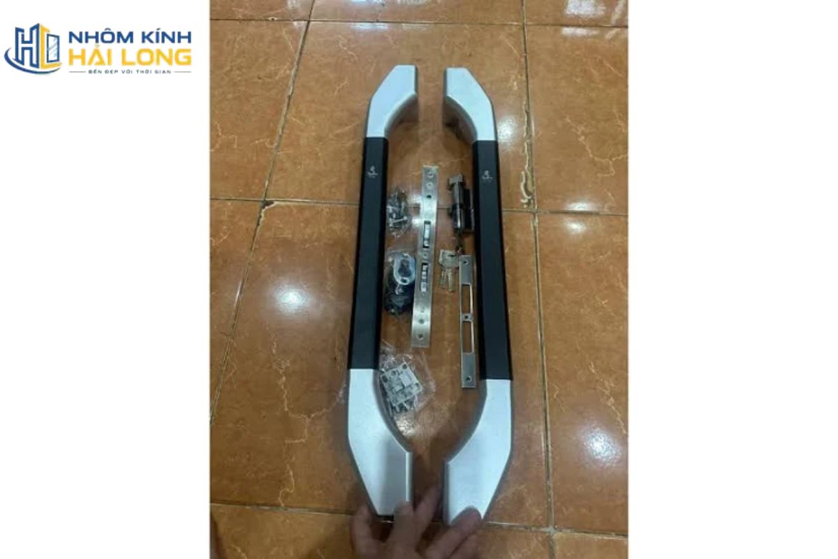 Phụ kiện cửa nhôm Xingfa xếp trượt gồm chốt cánh và thanh truyền động, giúp cố định cánh phụ vào khung hoặc cánh liền kề khi đóng cửa