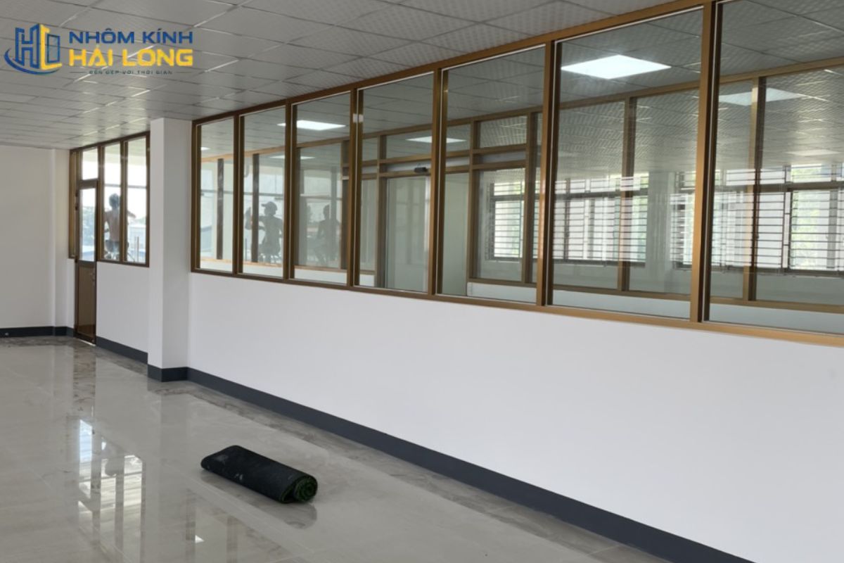 Vách kính khung nhôm hệ 1000 kết hợp lá nhôm có phần dưới che kín, phần kính phía trên lấy sáng, giúp tăng riêng tư và hạn chế va chạm